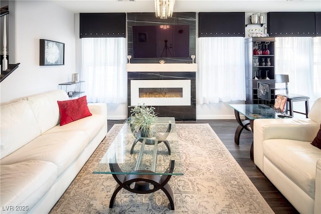 living room featuring a large fireplace, a wealth of natural light, and dark hardwood / wood-style flooring