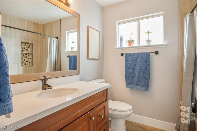 bathroom with vanity, toilet, and a healthy amount of sunlight