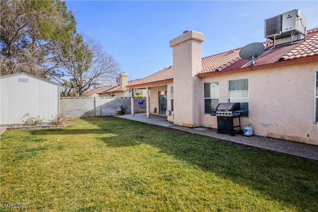 rear view of house featuring a yard, a patio area, and a storage unit