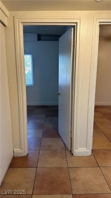 hall with tile patterned floors