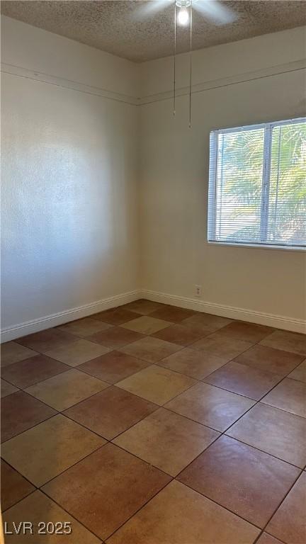 tiled empty room with a textured ceiling