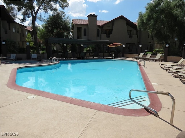 community pool with a patio area and fence