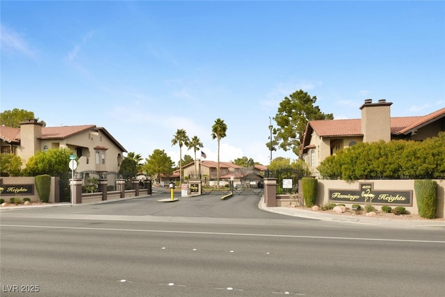 view of road with curbs, a gate, a gated entry, and a residential view