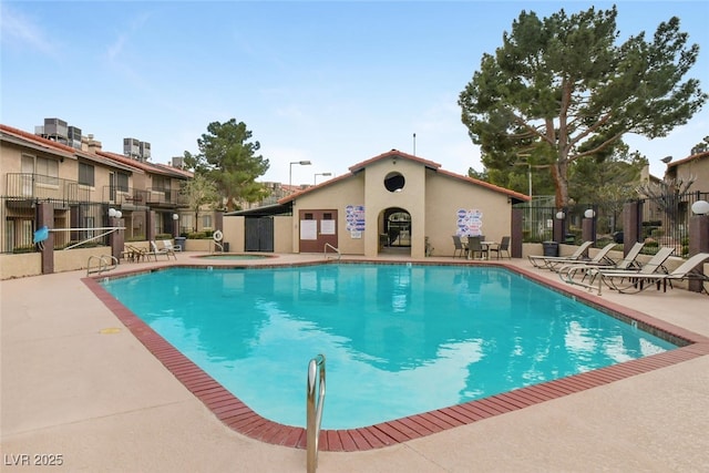 pool with a community hot tub, a patio area, and fence