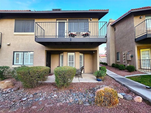 view of front of property featuring a patio area, a balcony, and stucco siding