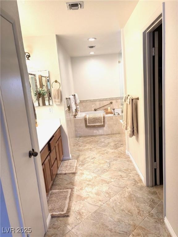 full bathroom with visible vents, a garden tub, vanity, and baseboards