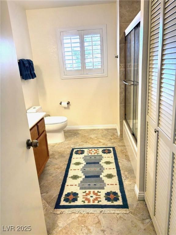 full bath with toilet, vanity, a shower with door, and baseboards