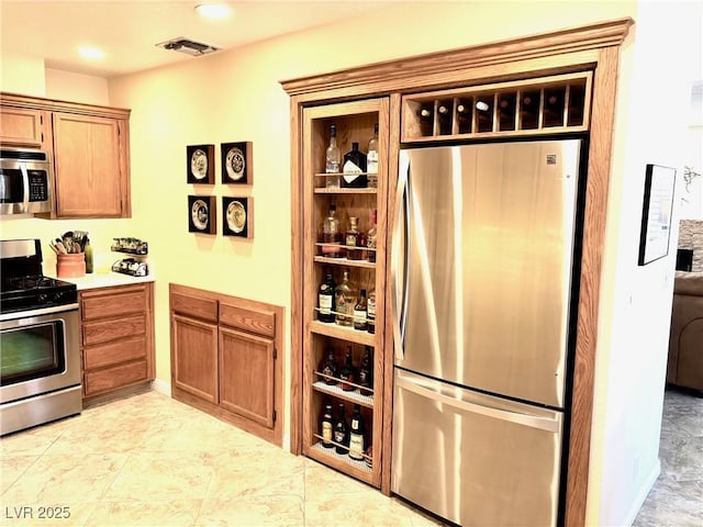 kitchen featuring brown cabinets, visible vents, stainless steel appliances, and light countertops