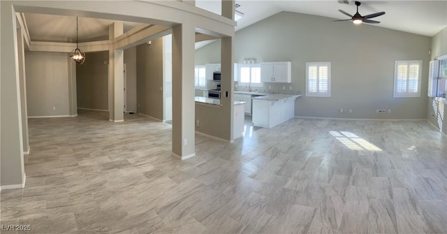 unfurnished living room with lofted ceiling and ceiling fan with notable chandelier