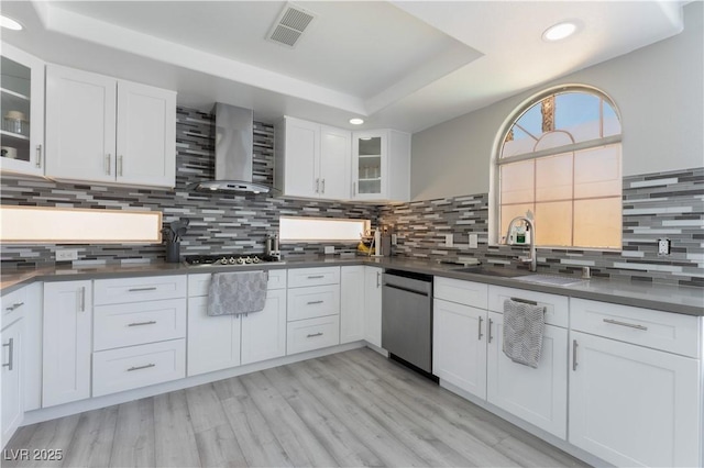 kitchen with white cabinets, a raised ceiling, wall chimney exhaust hood, and appliances with stainless steel finishes