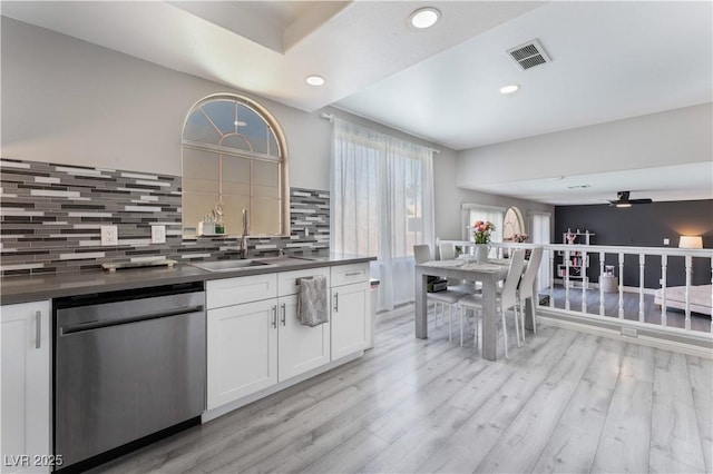 kitchen featuring sink, light wood-type flooring, stainless steel dishwasher, decorative backsplash, and white cabinets