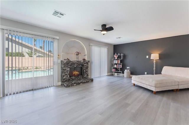 unfurnished living room featuring hardwood / wood-style flooring, ceiling fan, and a fireplace