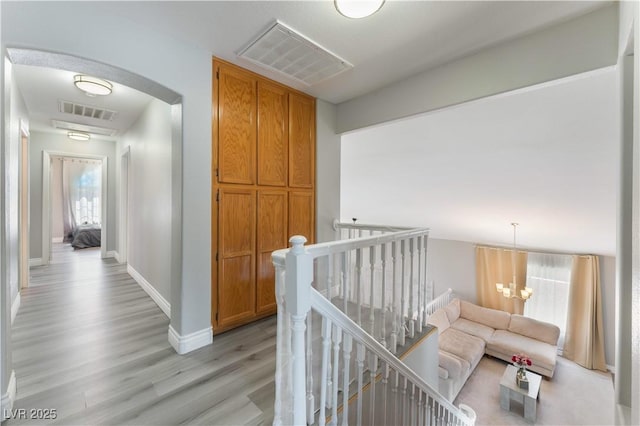 corridor featuring an inviting chandelier and light hardwood / wood-style floors