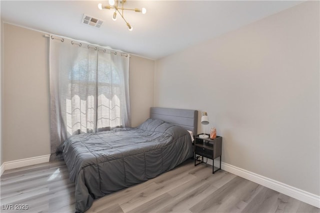 bedroom featuring an inviting chandelier and light wood-type flooring