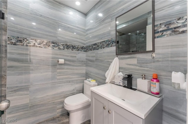 bathroom with vanity, tile walls, and toilet