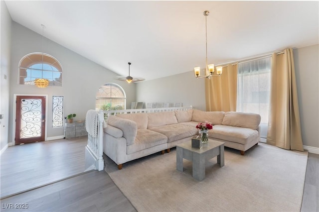 living room featuring wood-type flooring, ceiling fan with notable chandelier, and high vaulted ceiling