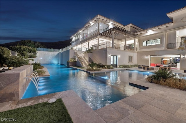 pool at twilight featuring pool water feature, a pergola, and a patio area