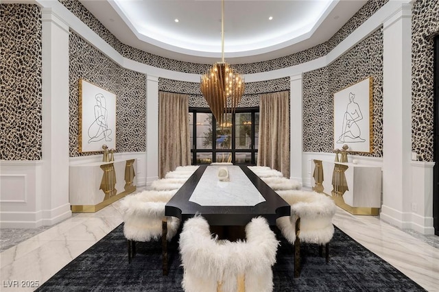 dining room featuring a chandelier, a decorative wall, marble finish floor, and a raised ceiling