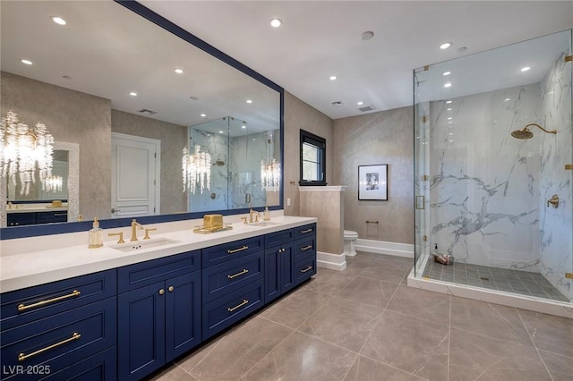 bathroom with a marble finish shower, double vanity, toilet, and a sink