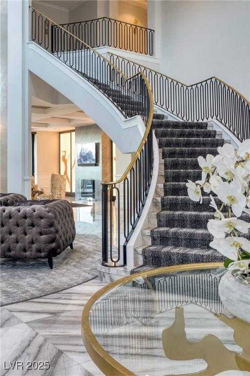 staircase featuring marble finish floor and a towering ceiling