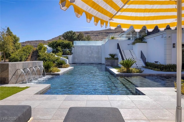 view of pool featuring stairs, fence, and a mountain view