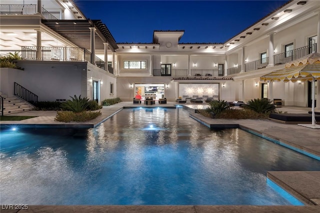 pool at night featuring stairway, a patio area, and an outdoor pool