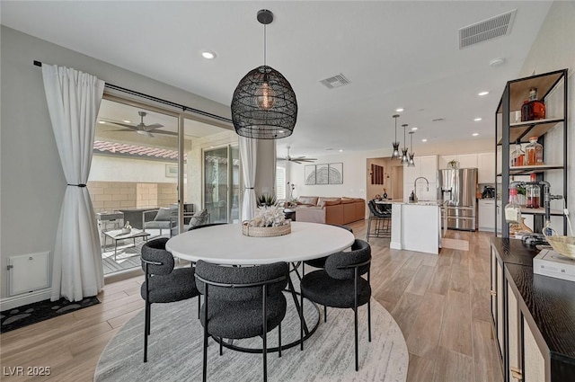 dining area with ceiling fan, sink, and light hardwood / wood-style flooring