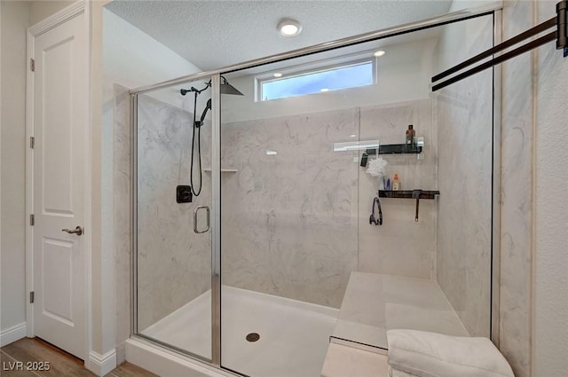 bathroom featuring wood-type flooring, a shower with door, and a textured ceiling