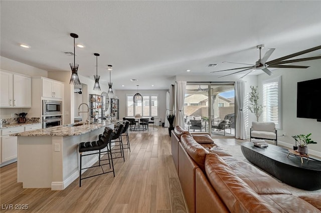 kitchen with stainless steel appliances, sink, hanging light fixtures, and white cabinets