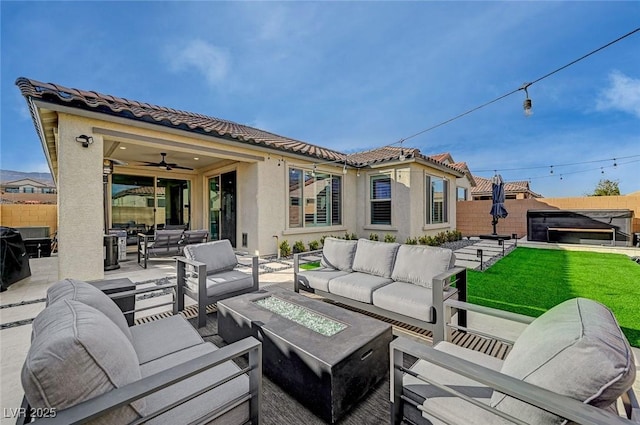 view of patio with ceiling fan and an outdoor living space with a fire pit