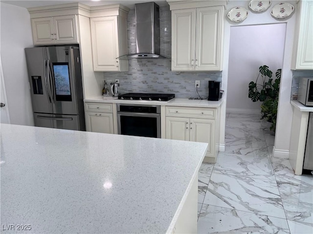 kitchen featuring tasteful backsplash, wall chimney range hood, and appliances with stainless steel finishes