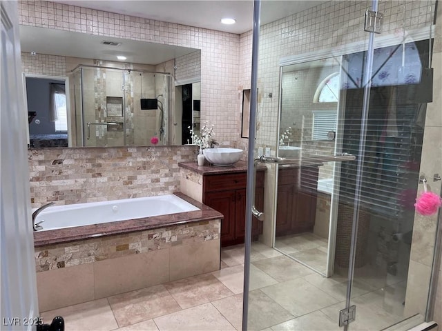 bathroom featuring plus walk in shower, tile walls, vanity, and tile patterned floors