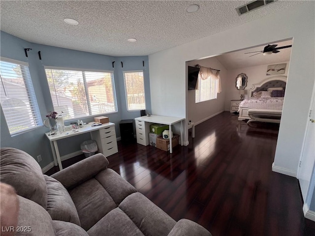 living room featuring ceiling fan, dark hardwood / wood-style floors, and a textured ceiling