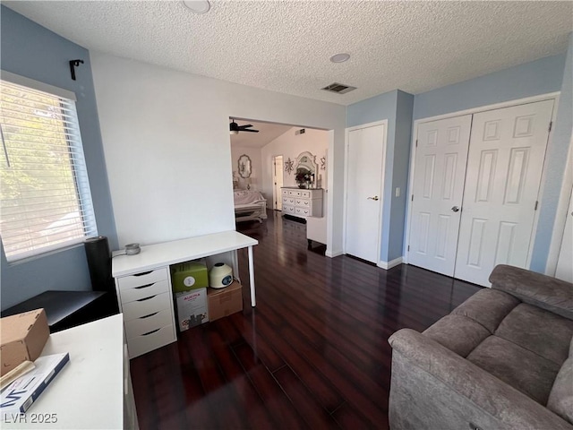 living room featuring ceiling fan, dark hardwood / wood-style floors, and a textured ceiling