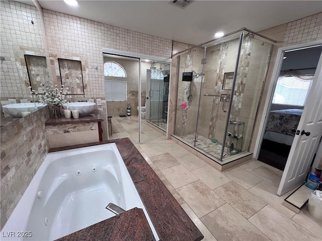 bathroom with vanity, independent shower and bath, and tile walls