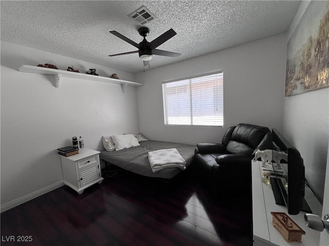 bedroom with ceiling fan, dark wood-type flooring, and a textured ceiling