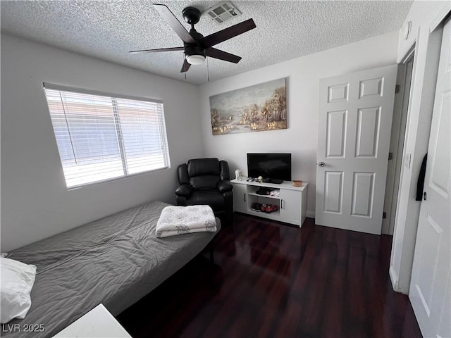 bedroom featuring ceiling fan, dark hardwood / wood-style floors, and a textured ceiling