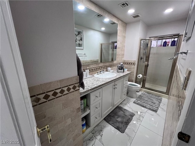 bathroom featuring vanity, toilet, tile walls, and a shower with shower door