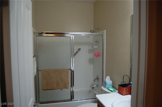 full bathroom with enclosed tub / shower combo, vanity, and toilet