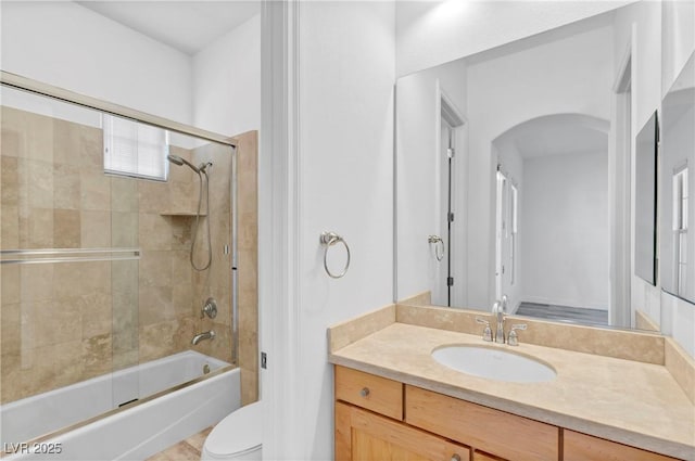 full bathroom featuring vanity, shower / bath combination with glass door, and toilet