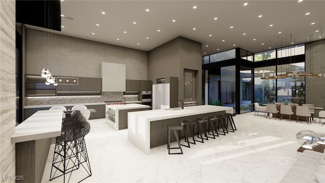 interior space with sink, stainless steel refrigerator, a kitchen breakfast bar, floor to ceiling windows, and a spacious island