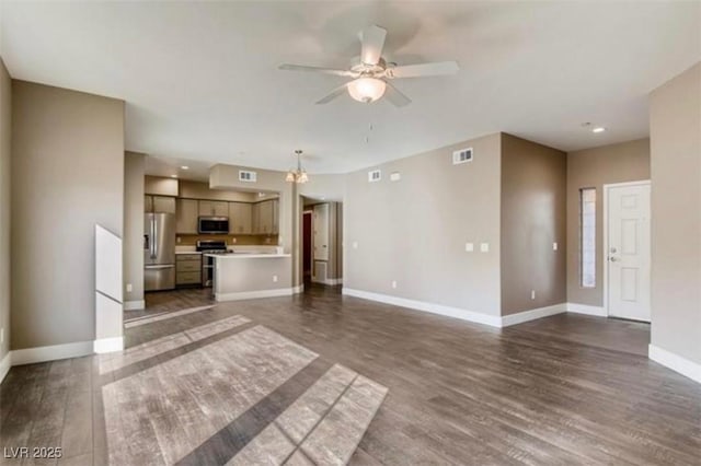 unfurnished living room featuring dark wood-type flooring and ceiling fan with notable chandelier