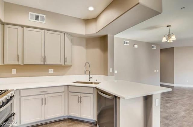 kitchen featuring sink, hanging light fixtures, appliances with stainless steel finishes, kitchen peninsula, and a notable chandelier