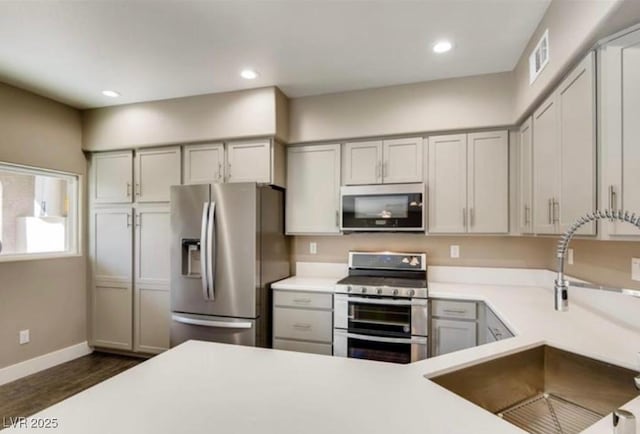 kitchen featuring stainless steel appliances, sink, and gray cabinetry