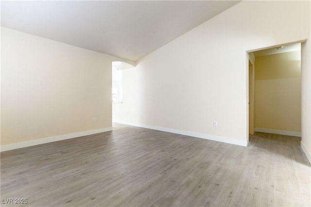 empty room featuring vaulted ceiling and light wood-type flooring