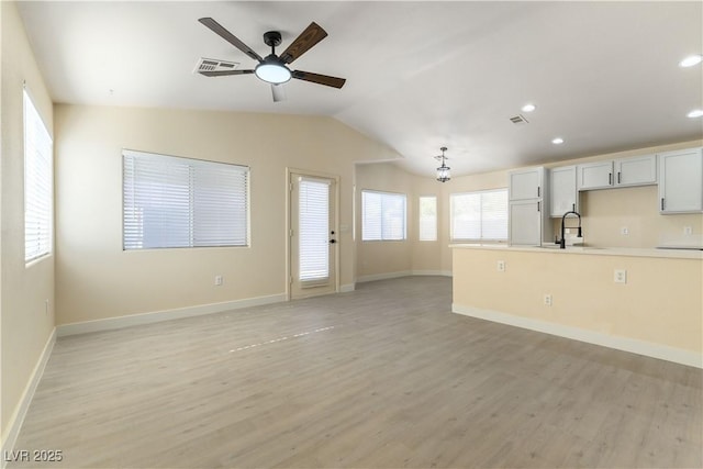 unfurnished living room featuring lofted ceiling, sink, light hardwood / wood-style flooring, and ceiling fan