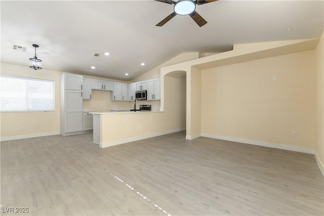 kitchen with appliances with stainless steel finishes, hanging light fixtures, light hardwood / wood-style floors, white cabinets, and vaulted ceiling