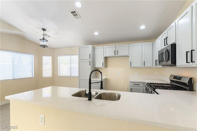 kitchen featuring sink, appliances with stainless steel finishes, hanging light fixtures, light stone countertops, and white cabinets