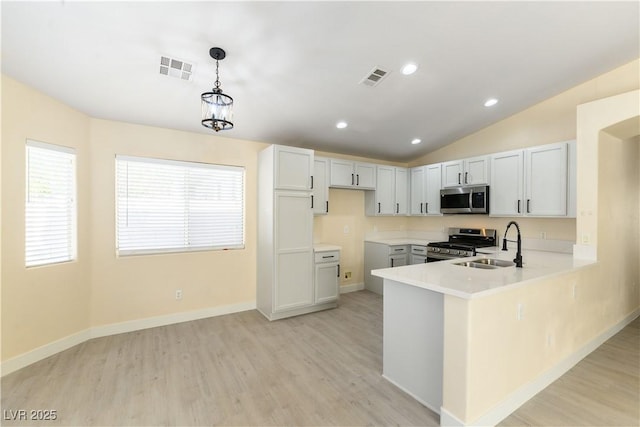 kitchen featuring vaulted ceiling, appliances with stainless steel finishes, pendant lighting, sink, and light hardwood / wood-style floors