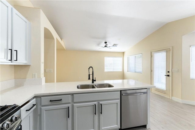 kitchen with lofted ceiling, sink, ceiling fan, stainless steel appliances, and kitchen peninsula